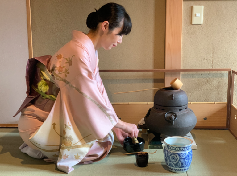 Woman in kimono preparing matcha during a private tea ceremony in Kyoto